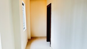 Un pasillo con piso de baldosas, una puerta y una lámpara fijada en la pared.