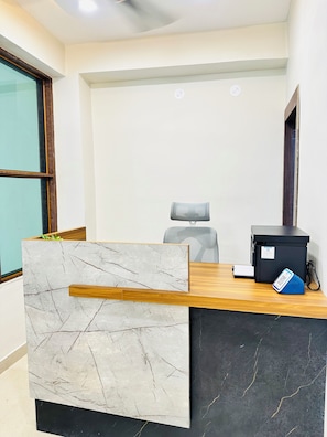 A reception desk with a marble panel, a black filing cabinet, and a grey office chair.