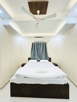 A modern bedroom with a bed, a ceiling fan, and an air conditioning unit.