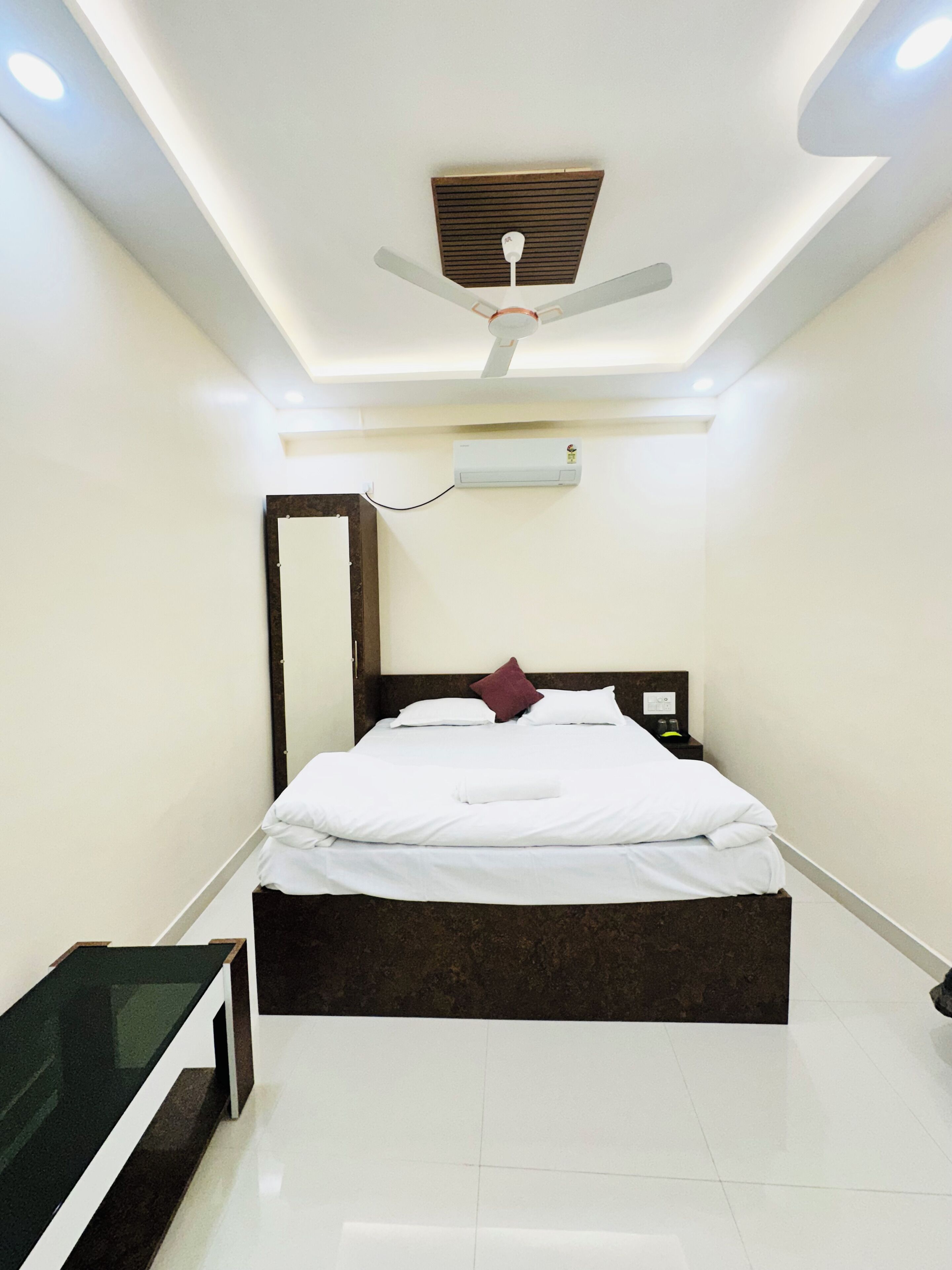 Un dormitorio moderno con cama, mesita de noche, ventilador de techo y aire acondicionado.
