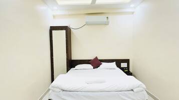 Un dormitorio moderno con cama, mesita de noche, ventilador de techo y aire acondicionado.