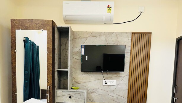 Un dormitorio con cama, armario, televisor montado en la pared y aire acondicionado mural.