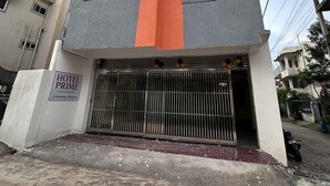 Un edificio de varios pisos con una llamativa banda naranja, entrada protegida por una reja y un letrero que indica que es un hotel.