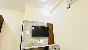 Habitación de hotel con una cama, un televisor montado, ventilador de techo y aire acondicionado.