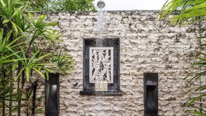 Eine Steinsäule mit Wasserspiel, darunter ein Wasserfall und eine Zierteil.