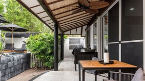 Eine Außenpatio mit Grill, Sitzgelegenheit und Blick auf den Garten.