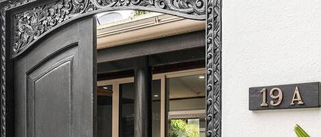 A black wrought iron gate with a house number sign '19A' on the wall.