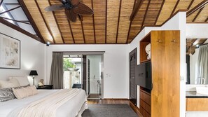 Ein Schlafzimmer mit einem Bett, einem Deckenventilator, einem Fernseher und einem Holzschrank.