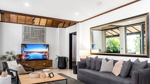 Ein modernes Wohnzimmer mit einem Flachbildfernseher, einer Couch, einem Couchtisch und einem großen Spiegel.