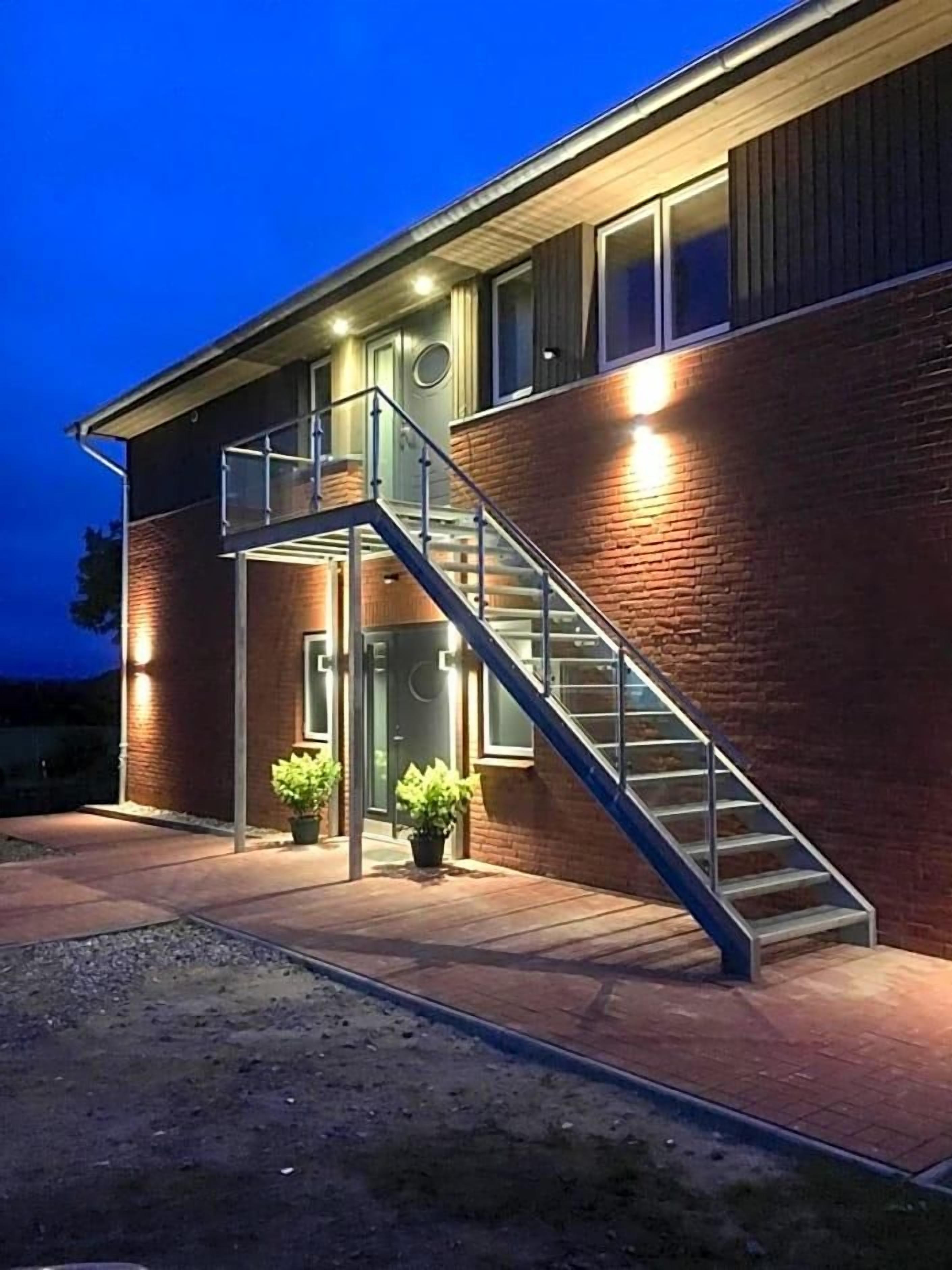 Ein Gebäude mit einer Treppe, die zu einer Tür führt, umgeben von Ziegelmauern und Blumentöpfen.