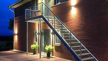 Ein Gebäude mit einer Treppe, die zu einer Tür führt, umgeben von Ziegelmauern und Blumentöpfen.