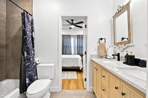 Ein modernes Badezimmer mit Badewanne, Toilette, Duschvorhang und Waschtisch mit Spiegel und Spüle.