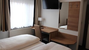 Une chambre d’hôtel comprenant un lit, un bureau, une chaise, une télévision et un miroir.