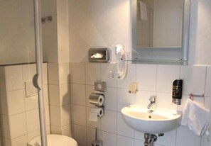 A bathroom with a toilet, a sink, a mirror, a towel rack, and a hand dryer. - Pension Buongusto (Steinmauern)