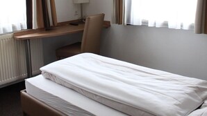 Une chambre d’hôtel avec un lit, un bureau, une chaise, une télévision et des rideaux.