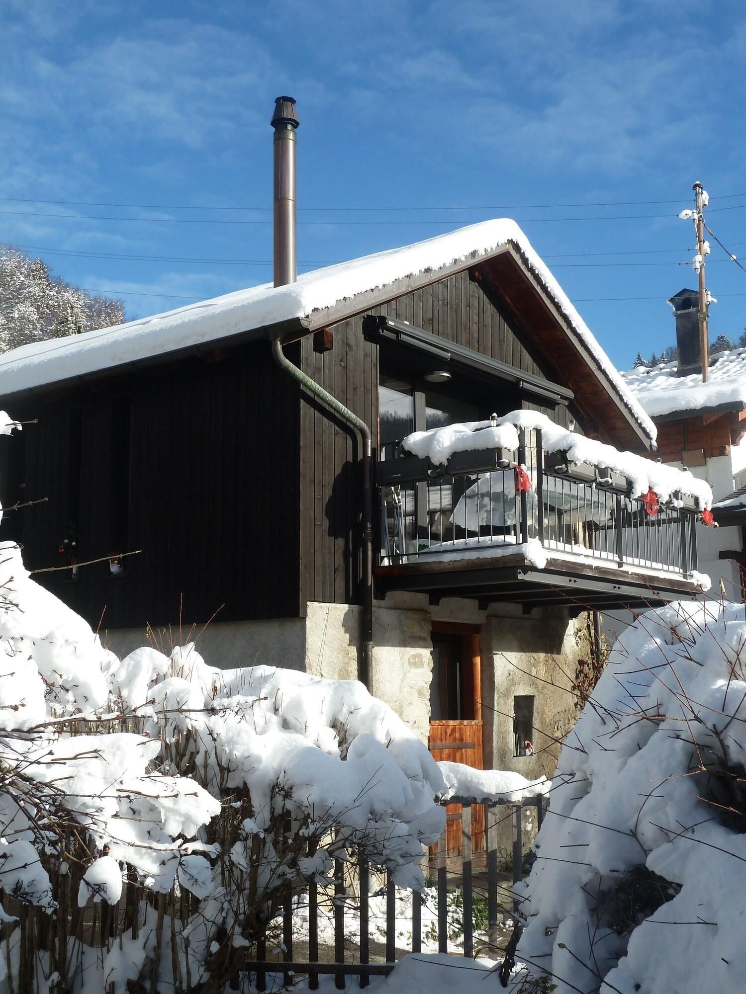 Uma cabana de madeira com varanda, rodeada por vegetação coberta de neve.