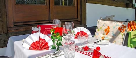 Una mesa para dos con mantel blanco, servilletas rojas y una decoración con forma de corazón.