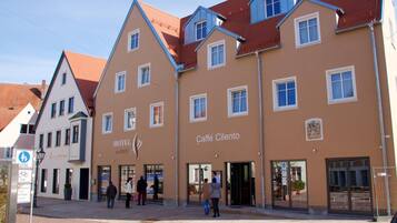 Ein Hotel im traditionellen europäischen Baustil, mit einem zentralen Eingang, Glasüren und einem Schild, das es als Hotel kennzeichnet.