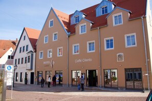 A hotel with a traditional European architectural style, featuring a central entrance with glass doors and a sign indicating it is a hotel. - Hotel Im Ried (Donauwoerth)