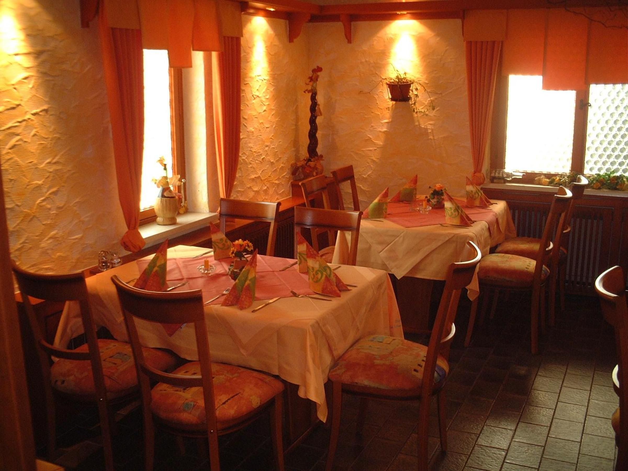 Een restaurant met meerdere tafels, stoelen en een rustieke inrichting.