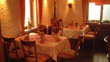 Een restaurant met meerdere tafels, stoelen en een rustieke inrichting.