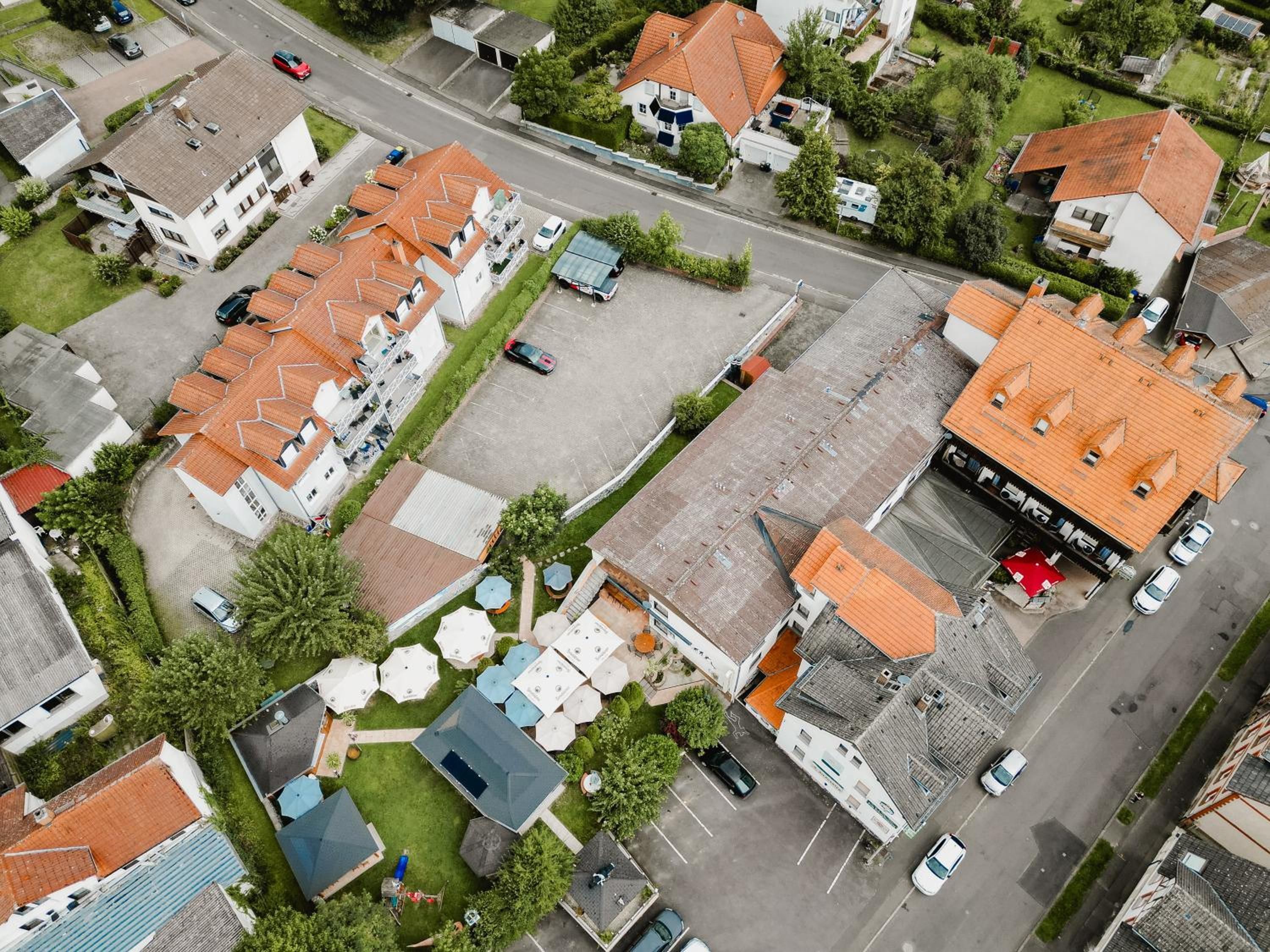 Luchtbeeld van een woonwijk met meerdere huizen, een hoofdstraat en een parkeerplaats.