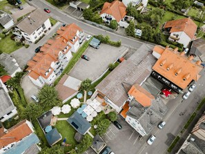 Ovenudblik over et boligområde med flere huse, en hovedvej og en parkeringsplads.