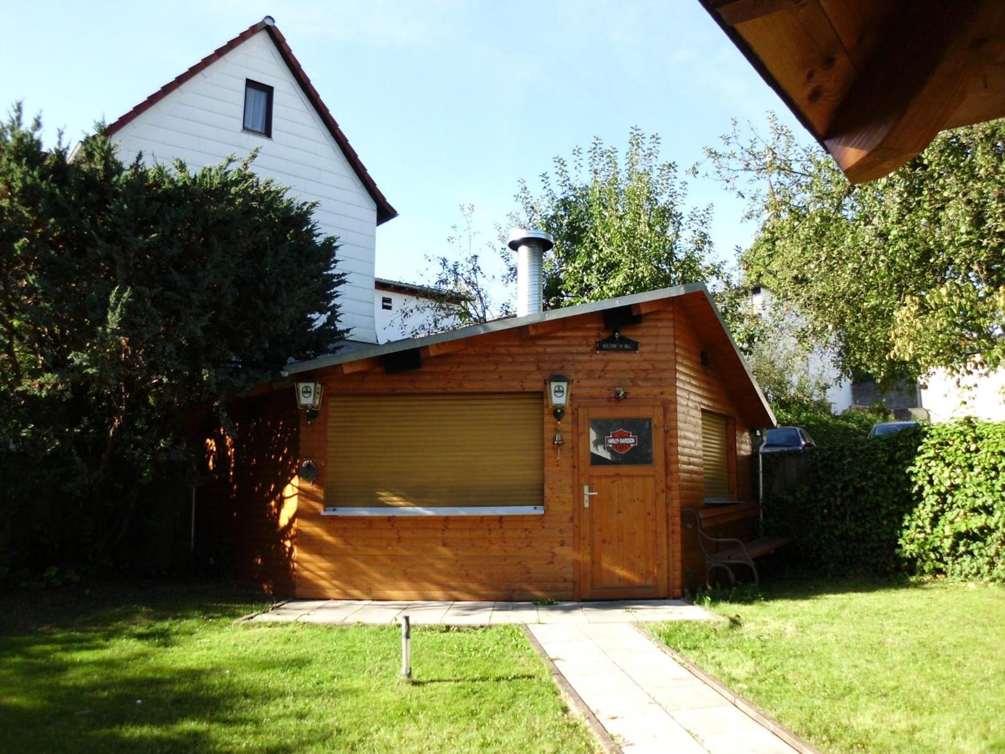 A wooden building with a garage door, a chimney, and a Harley-Davidson sign.
