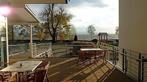 Une terrasse extérieure avec des tables et des chaises, une vue sur la mer et un belvédère.