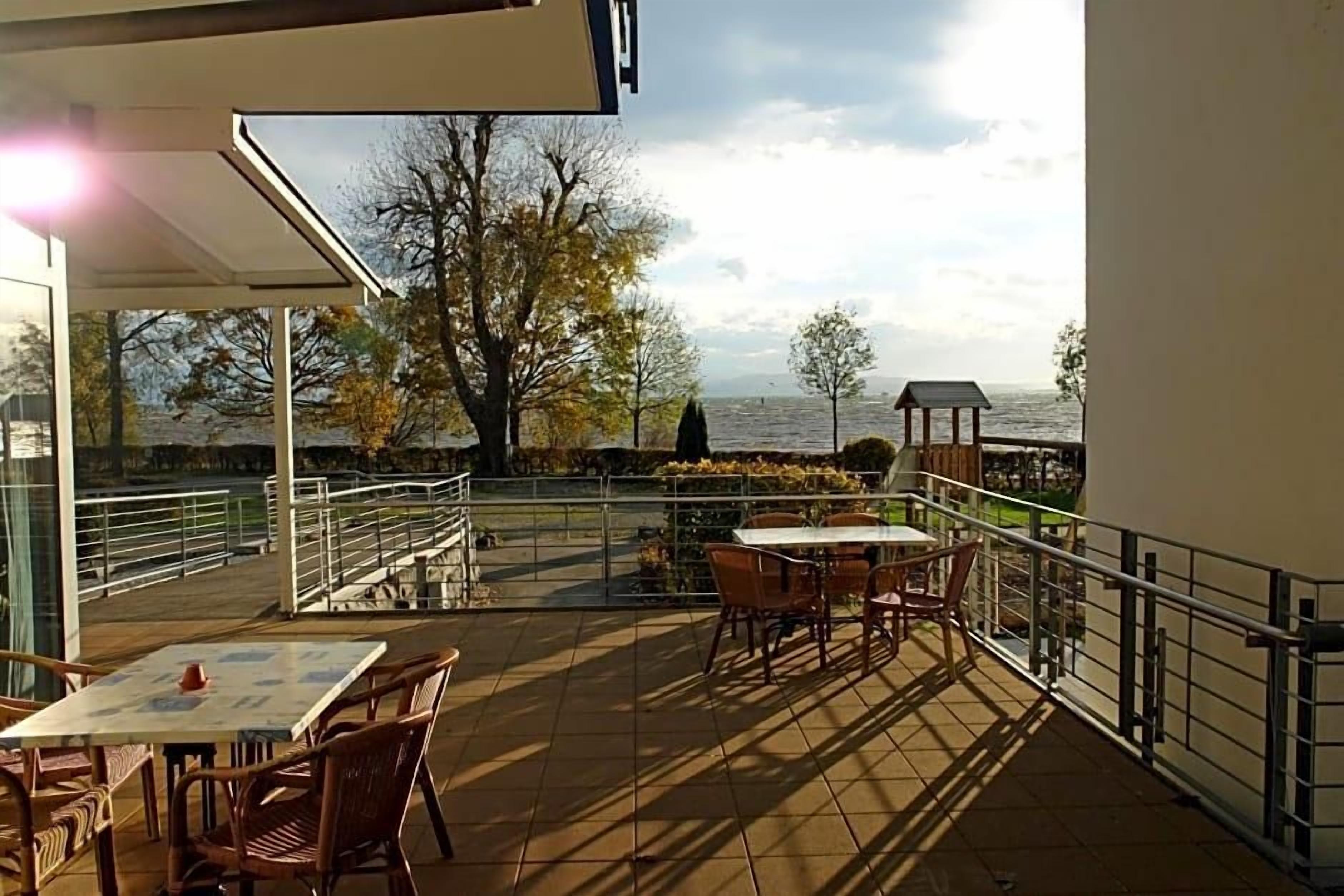 An outdoor patio with tables and chairs, a view of the sea, and a gazebo.