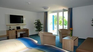 Une chambre d’hôtel équipée d’un lit, d’un bureau, d’une télévision, d’une chaise, d’une petite table et offrant une vue sur l’extérieur.