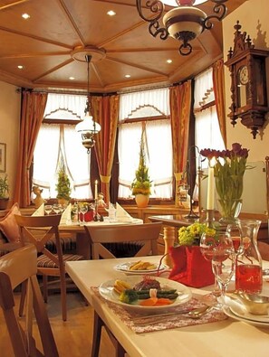 Ein Essbereich mit Tisch, Stühlen, einer Kandelaber und einer Wanduhr.