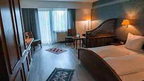 A hotel room with a bed, a desk, a chair, a lamp, and a view of the outdoors. - Hotel Bv Chner Garni (Bad Konig)