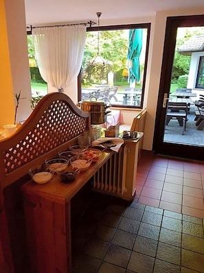 A room with a wooden bench, a radiator, and a window with a view of outdoor furniture. - Hotel Bv Chner Garni (Bad Konig)