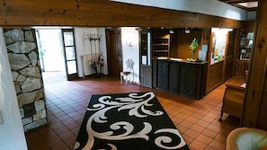 A lobby with a stone wall, a reception desk, and a chair. - Hotel Bv Chner Garni (Bad Konig)