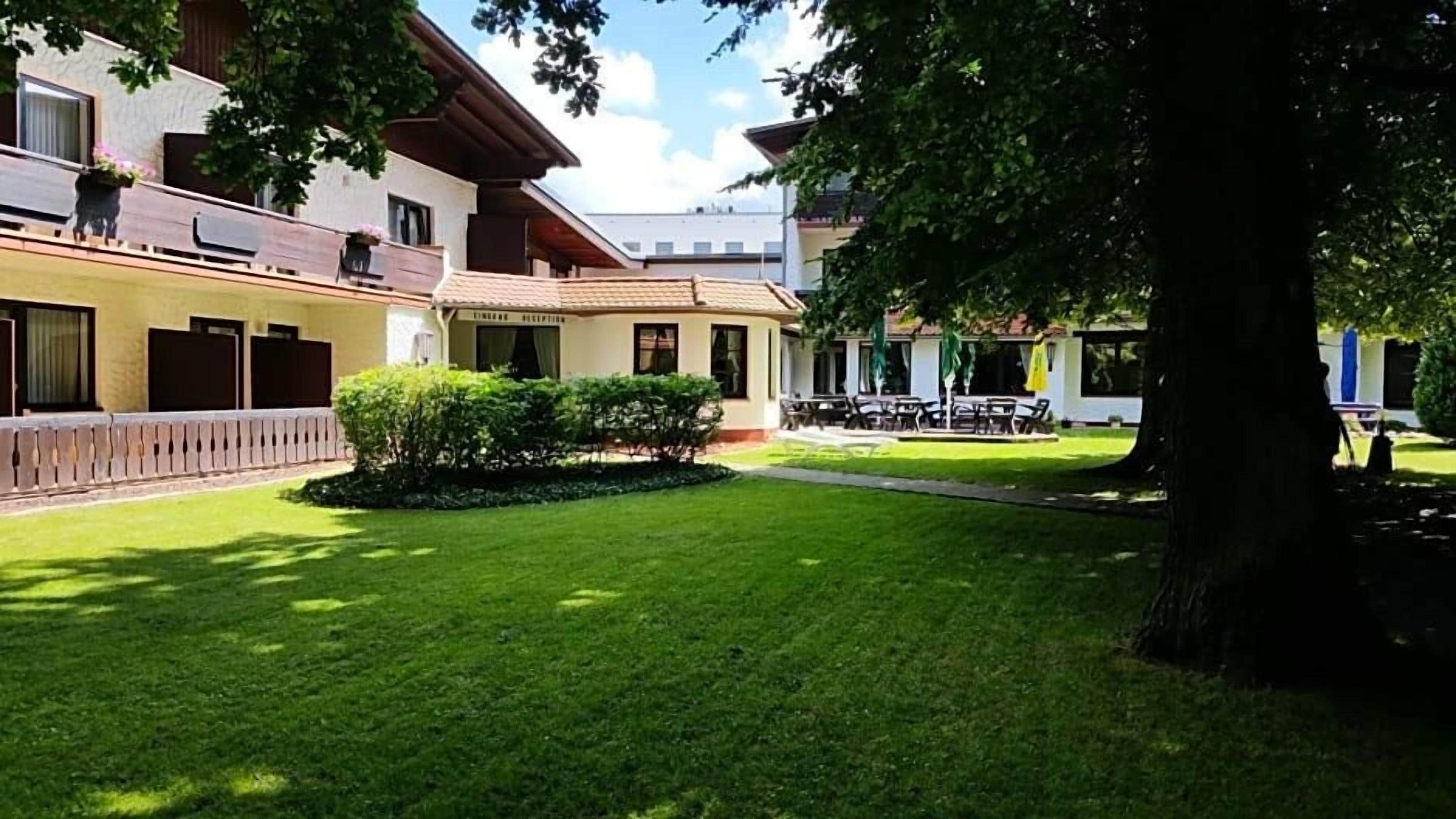 Ein Hotelinnenhof mit gepflegtem Rasen, einem Empfangsbereich und Sitzgelegenheiten im Freien.