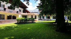 A hotel courtyard with a well-maintained lawn, a reception area, and outdoor seating. - Hotel Bv Chner Garni (Bad Konig)