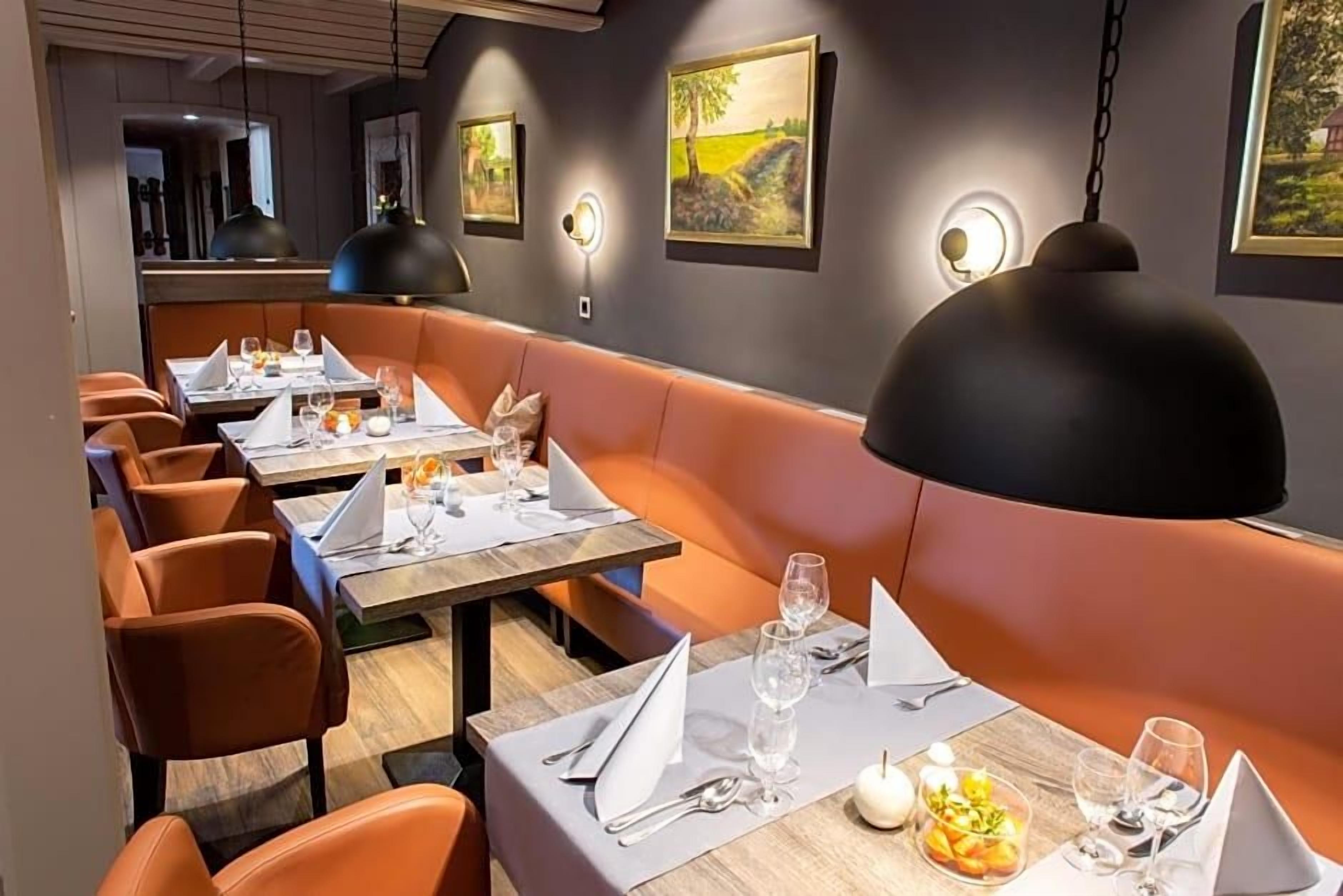 A restaurant with booths and tables, each set with cutlery and glasses.