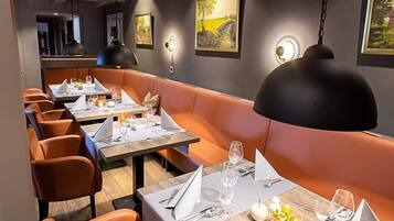 A restaurant with booths and tables, each set with cutlery and glasses.