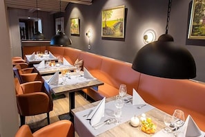 A restaurant with booths and tables, each set with cutlery and glasses. - Hotel Daub (Bremervörde)