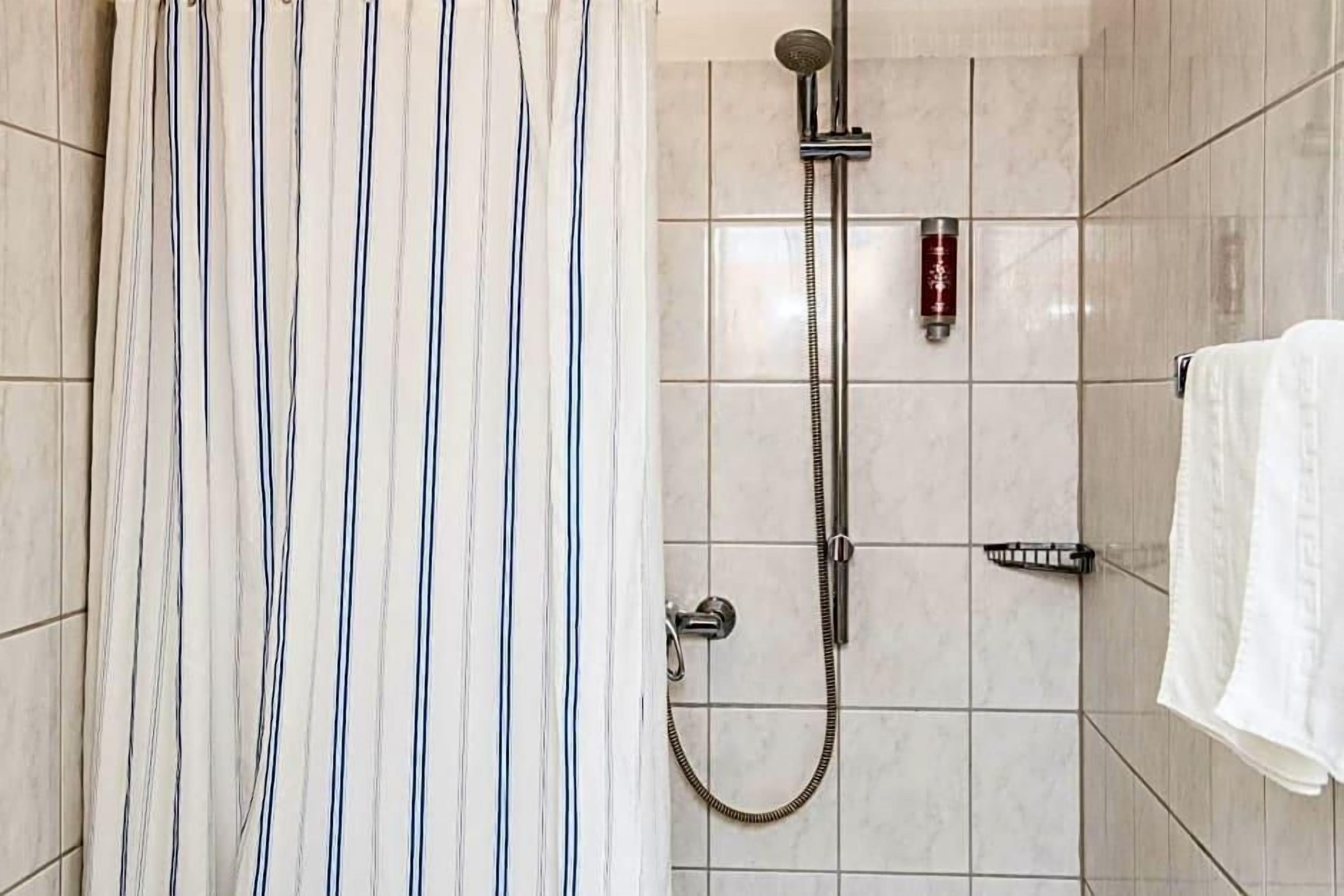 A shower with a handheld showerhead and a wall-mounted faucet.