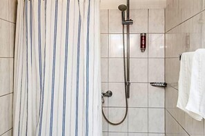 A shower with a handheld showerhead and a wall-mounted faucet. - Hotel Daub (Bremervörde)