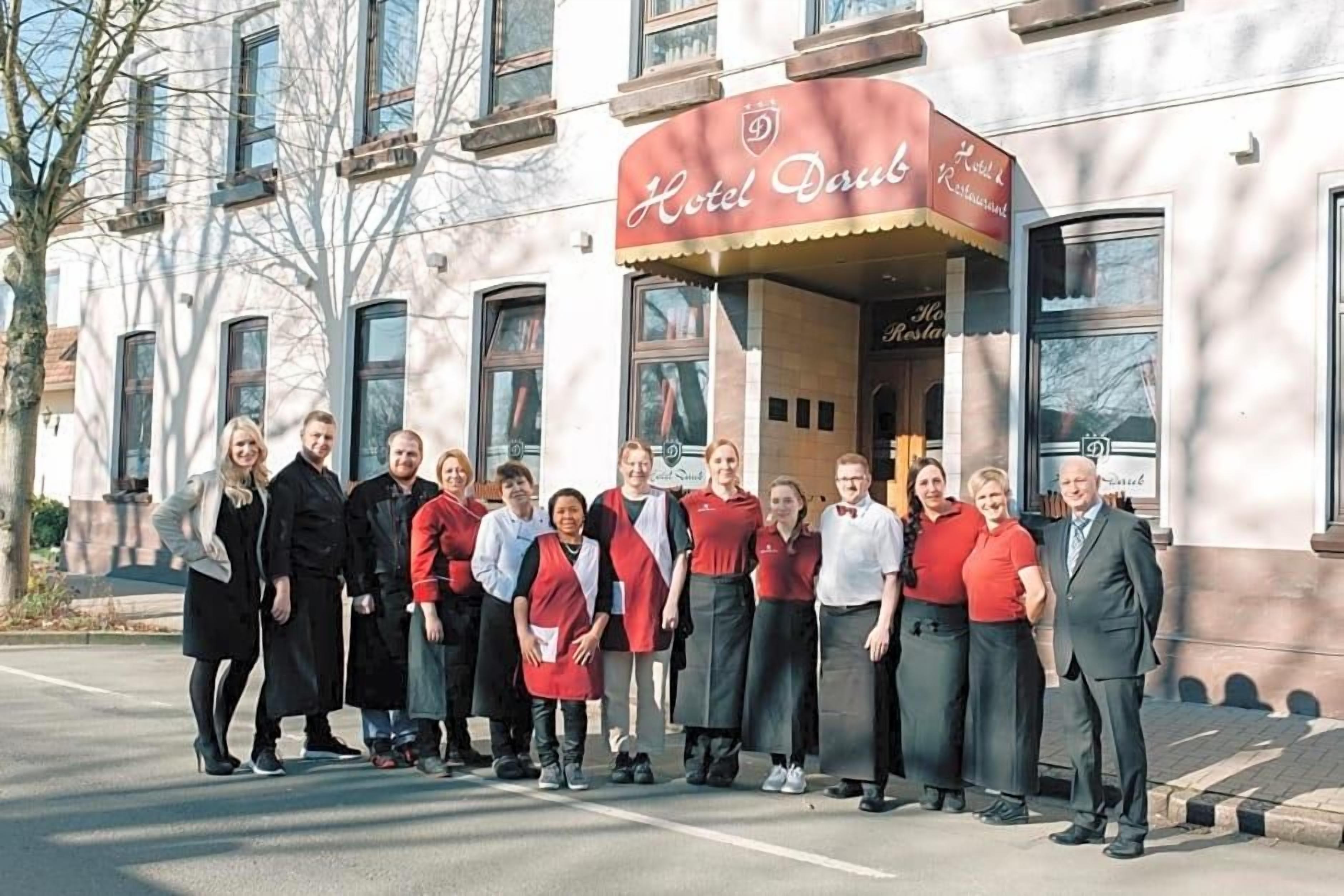 A group of people standing in front of a building with a sign that reads 'Hotel Doppel Restaurant.'