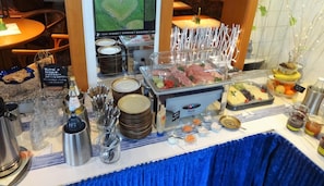A buffet setup with various food items, utensils, and condiments. - Ka Ka Hotel Garni (Warsow)