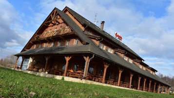A large wooden building with a steeply pitched roof, multiple windows, and a prominent sign.