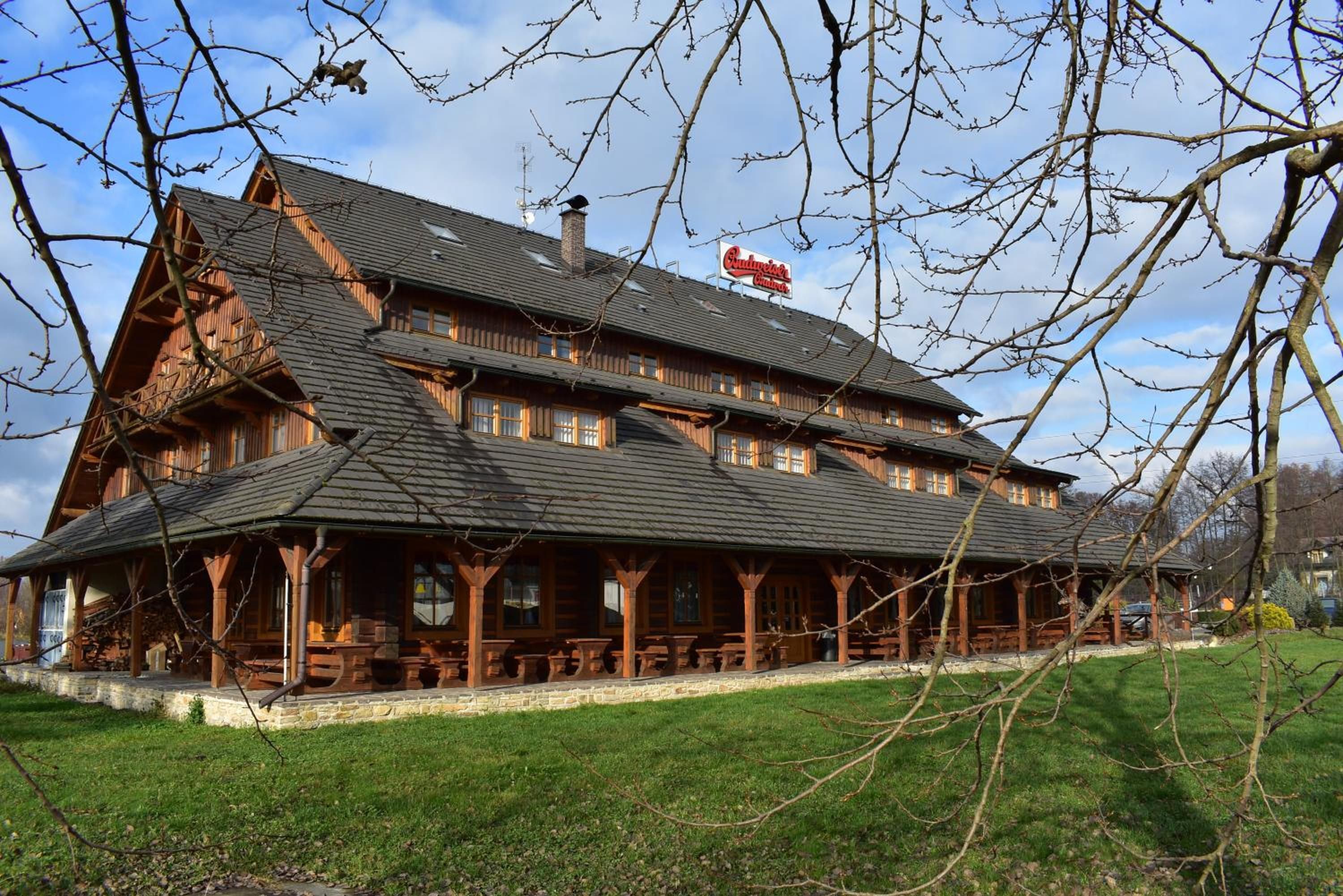 A traditional wooden building with a steeply pitched roof, multiple windows, and a sign for a restaurant.