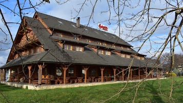 A traditional wooden building with a steeply pitched roof, multiple windows, and a sign for a restaurant.