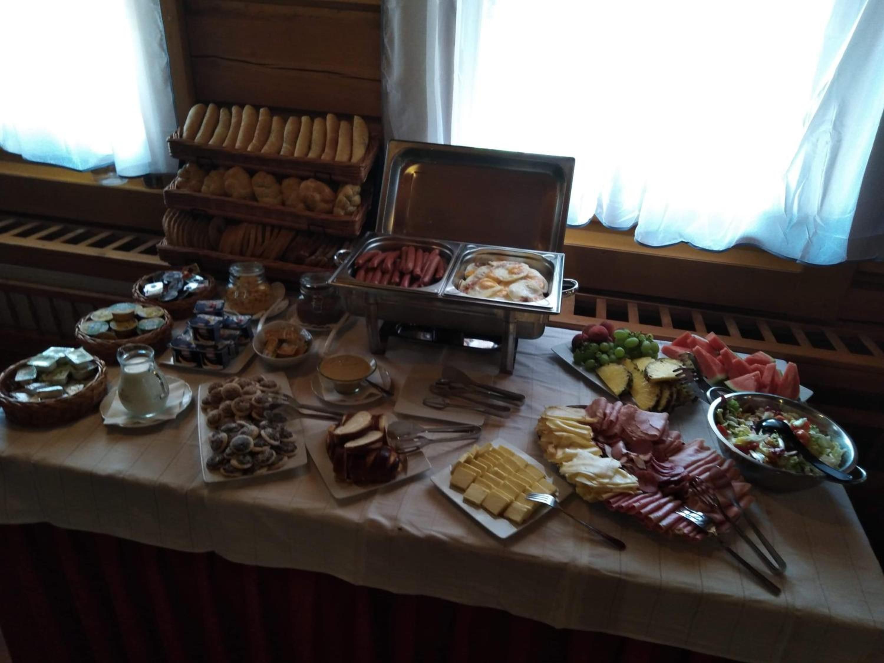A buffet table with various food items including bread, meats, cheeses, and fruits.