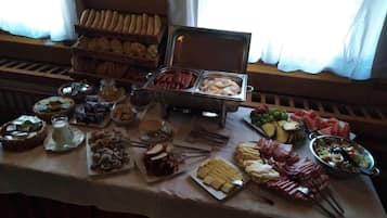 A buffet table with various food items including bread, meats, cheeses, and fruits.