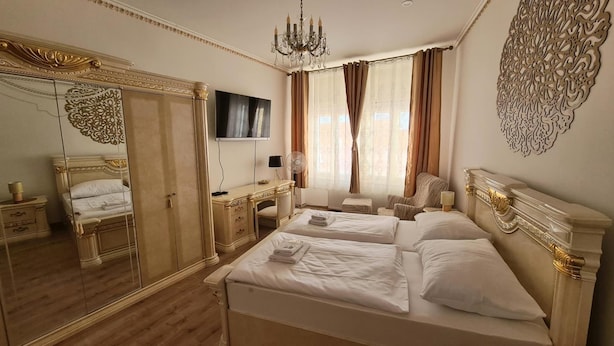 Una habitación de hotel con una cama grande, un escritorio, una silla, un televisor y un espejo.